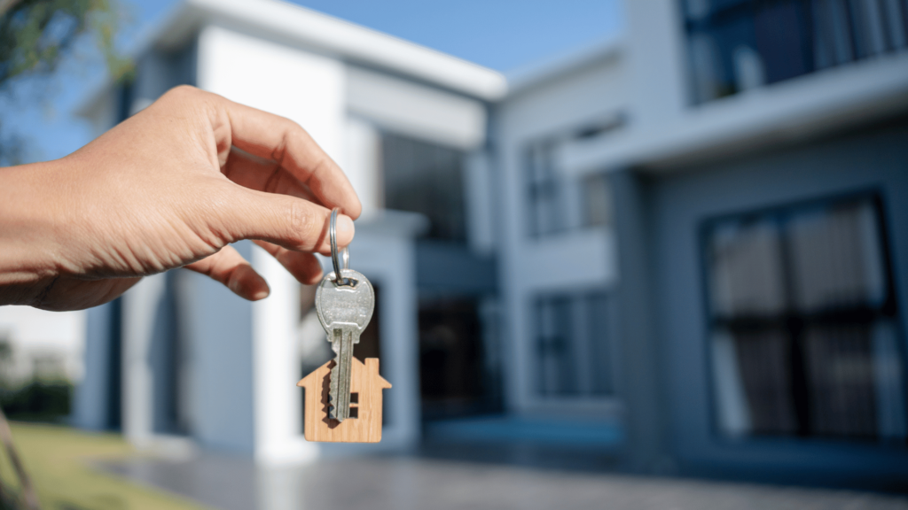 someone holding keys in front of a house for sale with an assumable mortgage