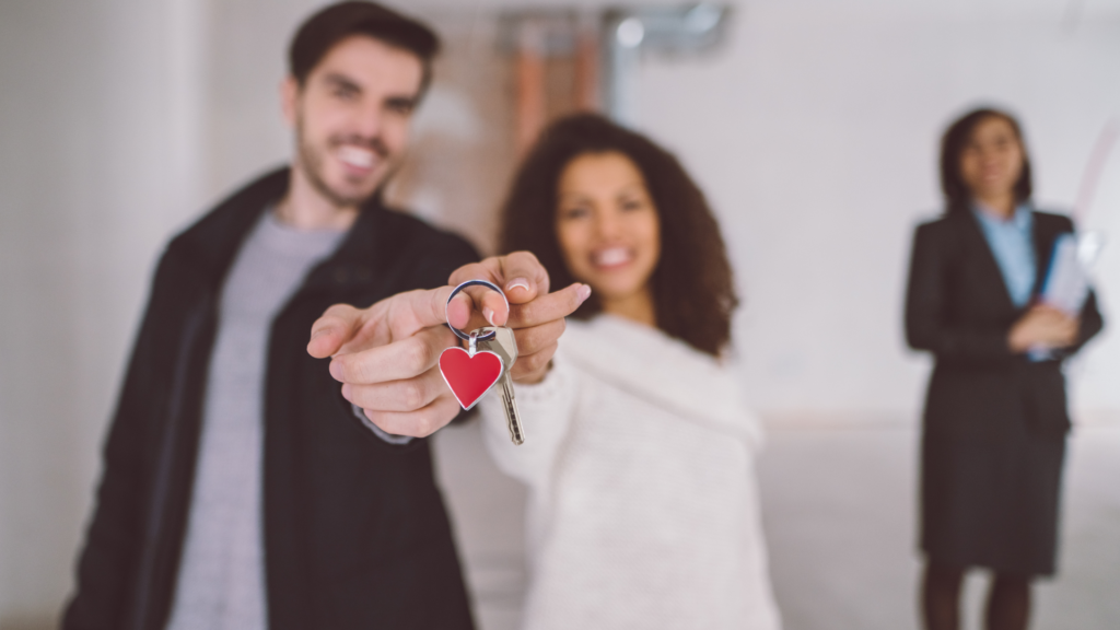 A man and a woman are showing off their new house keys following the purchase of their FHA assumable mortgage home. 