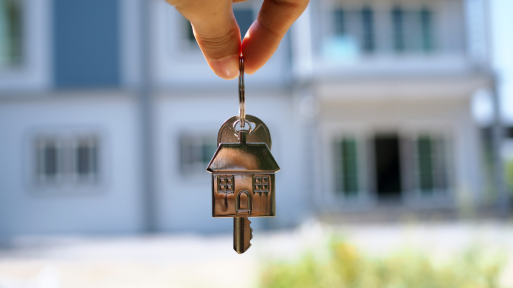 Someone is holding a set of keys with a home keychain signifying the sale of an assumable mortgage home. 