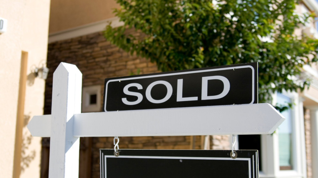 A black "sold" sign is located outside of a home for the blog focusing on "FHA Assumable Mortgage Guidelines Everyone Needs to Know." 