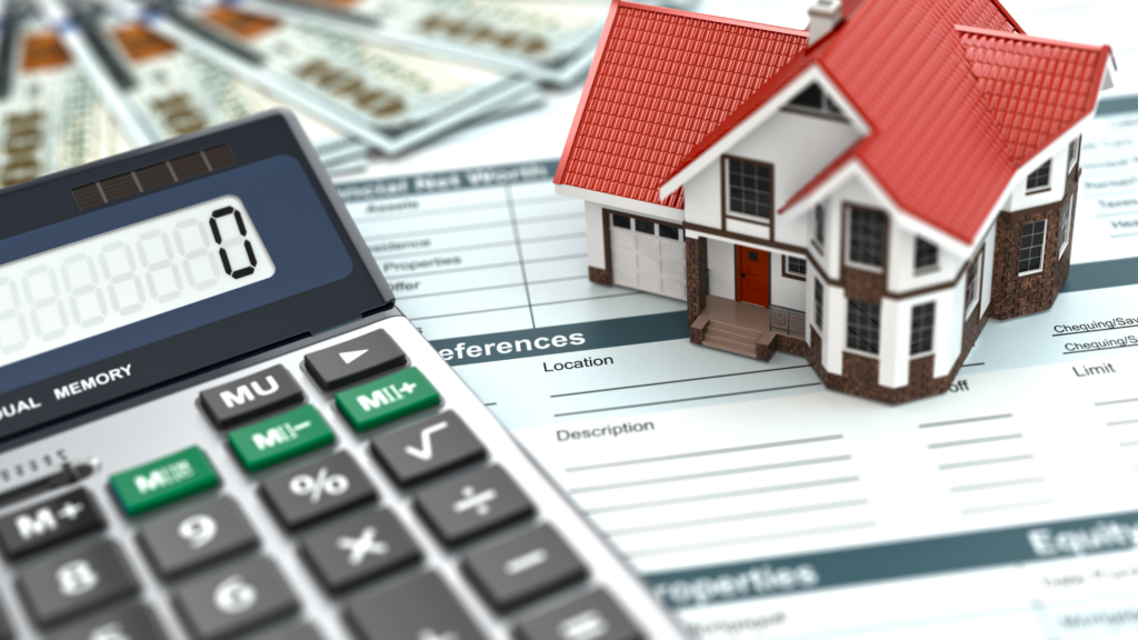 A calculator and miniature model of a home are sitting atop an assumable mortgage application. 