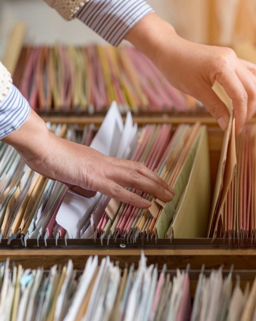 A picture of someone's hands looking through a filing cabinet.